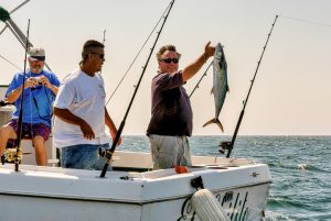 Three sports fishermen on a power boat, proudly show their catch of fish near Cabo San Lucas, Mexico.