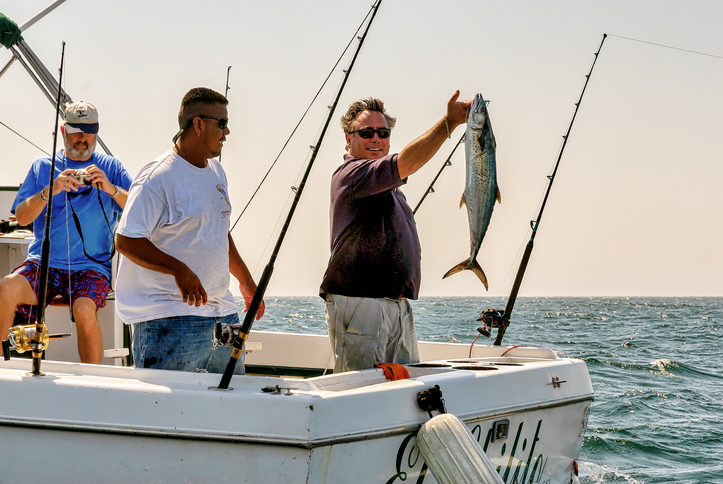 Three sports fishermen on a power boat, proudly show their catch of fish near Cabo San Lucas, Mexico.