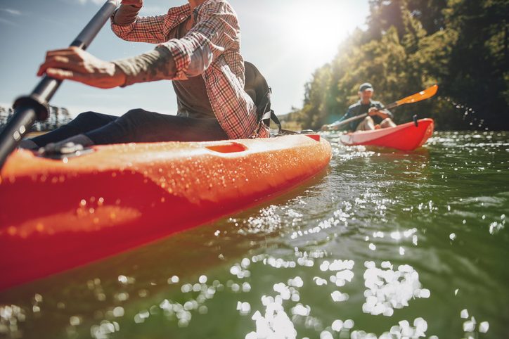 Cropped image of woman kayaking with a man in background. Couple canoeing in a lake on a summer day.